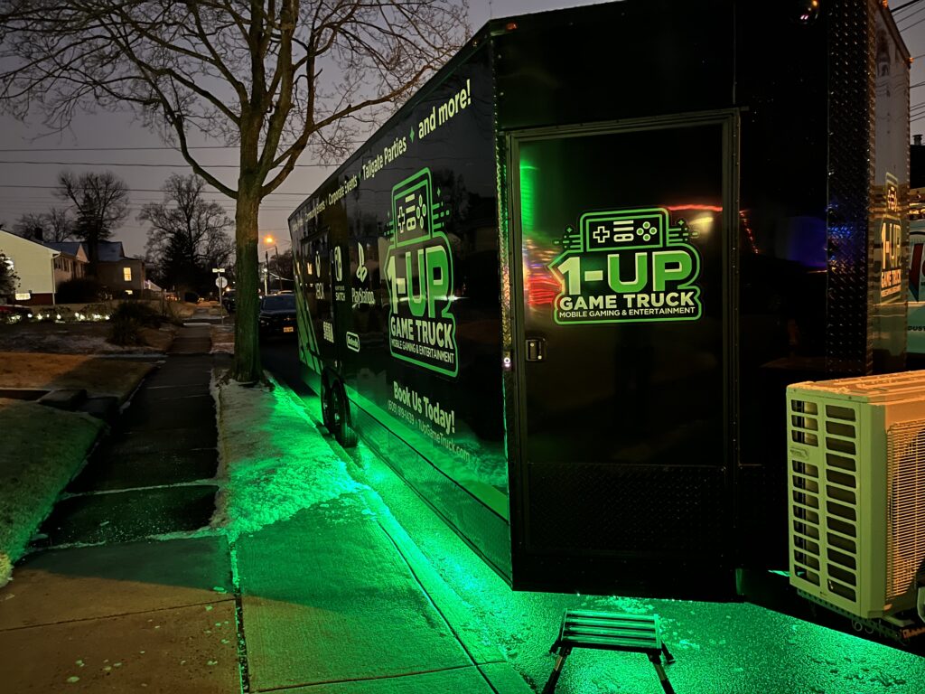 1-Up Game Truck nighttime exterior view with arcade style lighting